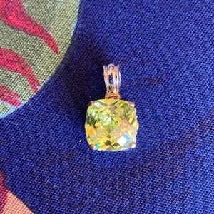 Silver tone pendant with gold tone accents, light greenstone with four prongs.